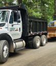 Dump truck with excavator on trailer in forest setting