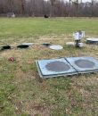 Septic cleaning in progress on grassy area with manholes and equipment
